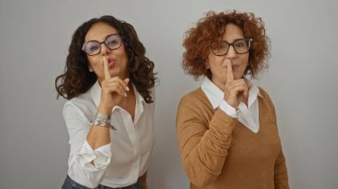 Birlikte poz veren kadınlar beyaz arka planda sırıtarak gizlilik ya da mahremiyet kavramına işaret ediyorlar..