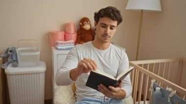 Genç adam rahat yatak odasında kitap okuyor. Oyuncak oyuncaklar ve yumuşak aydınlatmalarla çevrili, sıcak, davetkar ve sakin bir ortam yaratıyor..