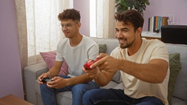 Baba ve oğul rahat bir oturma odasında video oyunlarını seviyorlar. Evlerinde İspanyol erkekleri arasındaki sevgi ve bağları gösteriyorlar.