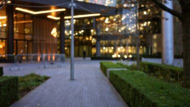 Kışın bulanık bir Londra caddesi manzarası. Odaklanamayan ışıklar, bokeh etkisi ve geceleri modern mimarinin yanından geçen bir adam..