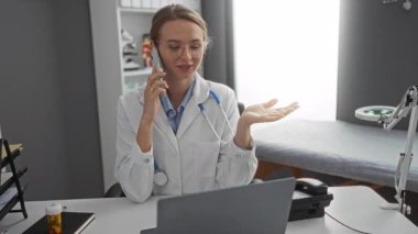 Tıbbi ekipman ve belgelerle bir hastane odasında telefonla konuşan, steteskop ve gözlük takan, klinik bir ortamda odaklanma ve profesyonellik gösteren bir kadın doktor..