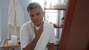 Bir güzellik salonunda aynada yüzünü inceleyen genç bir adam.