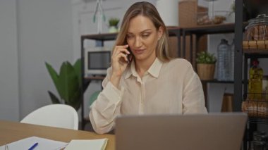 Ofiste dizüstü bilgisayarla konuşan bir kadın. Etrafı fabrikalar ve ofis malzemeleriyle çevrili. Profesyonel bir çalışma ortamı sergiliyor..