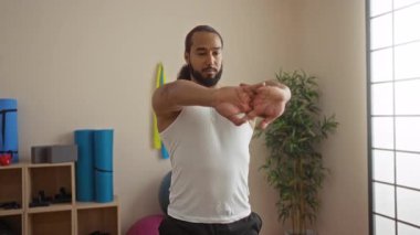 Yoga minderleri, bitkiler ve egzersiz malzemeleriyle sakin bir sağlık odasında esneyen adam, rahatlamayı somutlaştırıyor ve sakin bir spa ortamında odaklanıyor..