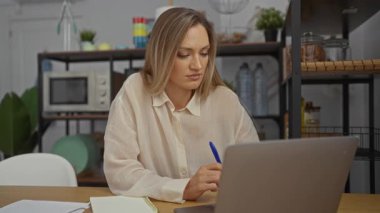 Ofiste çalışan bir kadın, elinde kalem tutarken bilgisayarına odaklandı. Etrafı ofis malzemeleri ve kapalı alan atmosferiyle çevriliydi. Profesyonel görevler için teknolojiyi kullanıyordu..