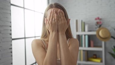 Kapalı mekanlarda gülümseyen elleri olan bir kadın modern dekorasyonlu parlak bir apartman dairesinde neşe saçar..