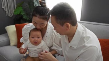 Anne ve baba, küçük oğullarını sıcak bir oturma odasında kucaklıyor ve sıcak bir aile anını içeride gösteriyorlar..