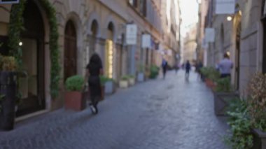 Roma 'nın tarihi merkezinde bir kaldırım taşı caddesinde yürüyen insanların bulanık bir görüntüsü. Odaklanmış arka planda büyüleyici eski kasaba mimarisi ve saksı bitkilerinin....