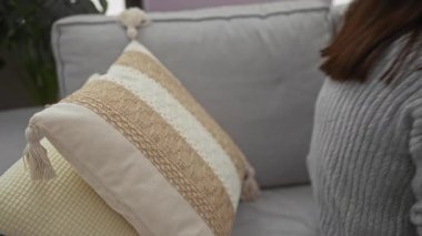 Oturma odasında akıllı telefon kullanarak evde dinlenen bir kadın rahat ve rahat bir yaşam tarzı sergiliyor..