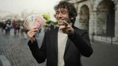 Şehrin dışında elinde Thai banknotları olan bir adam gülümseyerek bir jest yapıyor, hareketli bir sokak ortamında zenginlik ve kendine güven öneriyor..