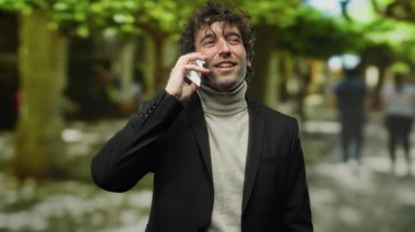 Açık havada akıllı telefonlardan konuşan yakışıklı, modern, kendine güvenen, güler yüzlü bir adam.