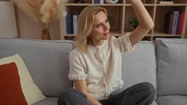 Modern bir oturma odasındaki rahat bir kanepede dinlenen kadın dekoratif elementler ve yastıklarla çevrili, sakin ve huzurlu bir atmosfer yayıyor..