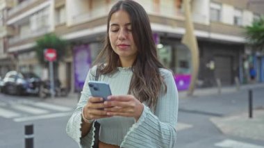 Şehir sokağında akıllı telefonuyla selfie çeken bir kadın yüzünde bir gülümsemeyle şehir yaşamının ortasında rahat bir an yaşıyor..