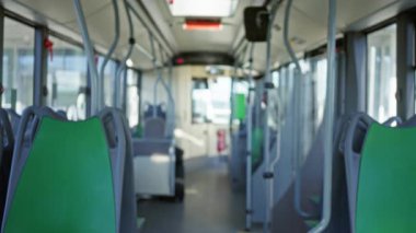 Yeşil koltuklara odaklanan boş bir otobüsün içi bulanık. Bokeh etkisi altında. Toplu taşımanın huzurlu ve sessiz atmosferini vurguluyor..