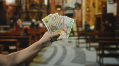 Bir kilisenin içinde Norveçli kronlar tutan adam, para biriminin farklı kullanımlarını gösteriyor..