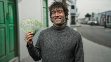 Elinde Rus rublesi banknotlarla gülümseyen bir adam bir şehir caddesinde halka açık bir ortamda finansal başarı ve mutluluk anı yakalıyor..