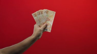Türkçe banknotlar tutan adam canlı kırmızı arkaplan gösterişli mali tema izole el ve para.