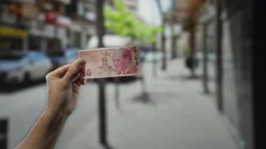 Şehir caddesinde bulanık şehir geçmişiyle el ele tutuşan Türk lirası banknotu..
