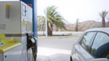 Bulanık benzin istasyonu sahnesi. Odaklanmış araba ve benzin pompası güneşli bir günde.