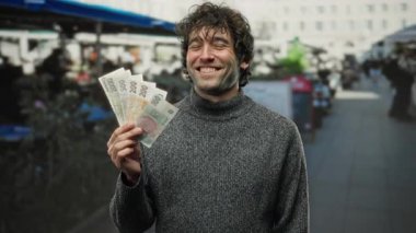 İspanyol adam, şehir merkezindeki bir açık hava lokantasının yakınındaki bir terasta mutlu bir şekilde Czech Koruna banknotları tutuyor..