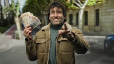 Bir şehir caddesinde elinde Türk lirası tutan İspanyol bir adam. Kahverengi bir ceket giyerken gülümseyip işaret ediyor. Şehir hayatını ve finansal başarısını gözler önüne seriyor..