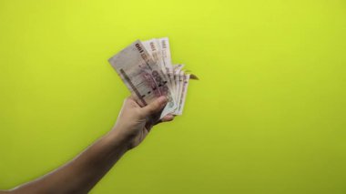 Suudi riyal banknotları tutan adam izole edilmiş sarı arka planda para kavramını gösteriyor.