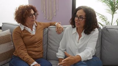 Kadınlar rahat bir oturma odasında kanepede konuşuyorlar. Bitkiler ve dekorla orta yaşlı arkadaşlıklar sergiliyorlar. Rahat bir ev ortamını ön plana çıkarıyorlar..