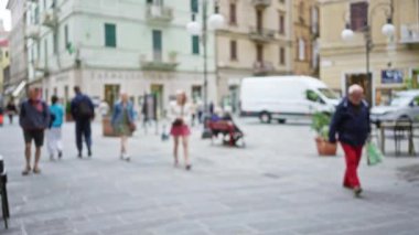 İnsanlar La Spezia, İtalya 'da bulanık bir sokak sahnesinde yürüyorlar. Bokeh etkisindeki erkek ve kadınlarla birlikte, dağılmış binaları ve sokak hayatını gösteriyorlar..