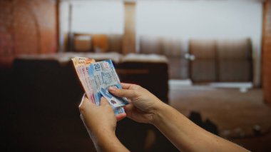 Bir inşaat sahasında Meksika pezosu tutan adam şehir ortamında yatırım ve finansal planlamayı vurguluyor..