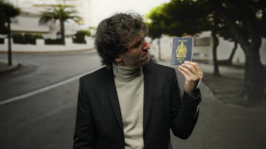 Elinde Kanada pasaportu olan bir adam şehir sokaklarında duruyor, şehir ortamında seyahat ve kimlik sergiliyor, cinsiyet ve ulusal kimlik temalarını vurguluyor..
