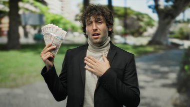 İspanyol bir adam parkta elinde Suudi Arabistan rakipleri tutarken diğerini göğsüne yerleştiriyor. Manzaralı bir arkaplana karşı duygu ve başarı aktarıyor..