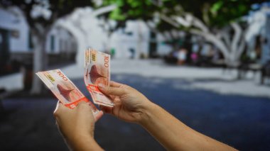 Kentsel bir sokakta Norveç kronu banknotları tutan bir adam, bir şehir ortamında para işlemleri ve yatırım fırsatlarını vurguluyor, finansal kavramları vurguluyor.