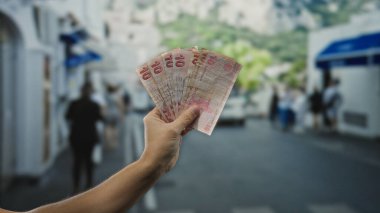 Kalabalık bir şehir caddesinde elinde Türk lirası banknotları tutan adam, finans ve açık şehir ortamında seyahat etmenin özünü yakalıyor..