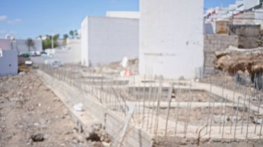 Tamamlanmamış bina temelleriyle bulanık bir inşaat alanı. Odaklanmamış arka plan ve dağınık enkaz arasında.