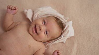 Yeni doğmuş sevimli erkek bebek, sıcak yatak odasındaki yumuşak yatakta gülümsüyor, masum çocukluk sevincini ve sıcaklığını sevgi dolu bir evde yakalıyor..