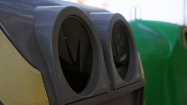 Kentsel atık yönetimi ve güneşli gökyüzü altında çevresel sürdürülebilirliği vurgulayan modern tasarıma sahip açık hava geri dönüşüm konteynırının yakın görüntüsü