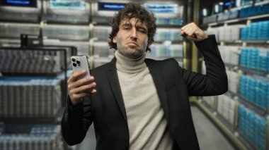 Takım elbiseli İspanyol bir adam süpermarkette kendine güvenerek kollarını esnetiyor, elinde akıllı bir telefonla gücünü gösteriyor, dinamik ve modern bir atmosfer yaratıyor..
