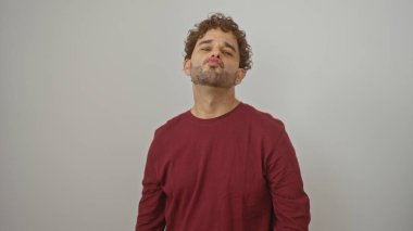 İzole edilmiş beyaz arka planda poz veren genç İspanyol adam. Günlük kırmızı gömlek portresi içinde kendine güven ve cazibe yayıyor.