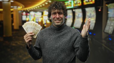 İspanyol adam kumarhanede elinde Norveç kronuyla kumar makinelerinin arasında para karmaşası içinde..
