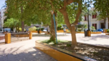 Bulanık park arka planı ağaçlarla dolu ve güneşli bir günde odakları kesilmiş insanlar canlı bir bokeh etkisi yaratıyor