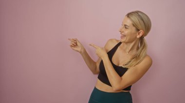 İzole edilmiş pembe bir arka plana gülümseyen, neşeli ve çekici bir ifade sergileyen bir kadın..