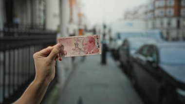 Bir şehir caddesinde elinde Türk lira banknotuyla gezen adam, kalabalık bir ortamda şehir yaşamını ve finans konularını yakalıyor..
