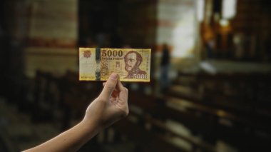 İç mekan kilise ortamında el ele tutuşan Macar banknotları, dinsel bir ortamda paranın altını çizmek, ayrıntılı bir şekilde ele geçirilmiş..