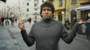Şehir caddesinde İngiltere banknotlarını elinde tutan adam, karışık bir ifadeyle, mali belirsizlik ve para birimini hareketli bir şehir ortamında somutlaştırıyor..