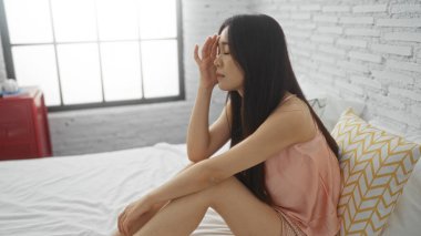 Beyaz tuğlalı duvarları olan parlak bir yatak odasında uzanan kadın, modern bir evde sakin ve sakin bir atmosferi yansıtıyor..