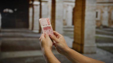 Kentsel bir ortamda İsviçre Krona 'yı tutan eller, bir şehir caddesinde finansal işlemleri, iş ve yatırım fırsatlarını resmediyor.