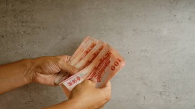 Somut bir arkaplan karşısında Tayvan dolarlarını tutan eller para ve finansal kavramları resmediyor.