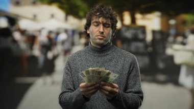 Şehir dışındaki işlek bir caddede elinde Czech Koruna banknotları tutan İspanyol bir adam, finansal başarıyı resmediyor ve şehir ortamında seyahat ediyor..