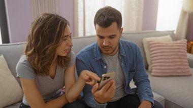 Bir çift evdeki kanepede oturup rahat bir oturma odasında akıllı telefondan bir şeyler tartışıyor.