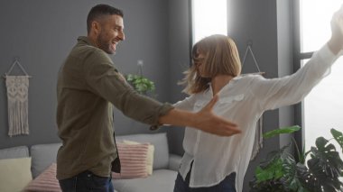 Mutlu çift, çiçeklerle dolu bir salonda birlikte dans ediyor, neşeli ilişkilerini ve evdeki güzel bağlarını vurguluyor..